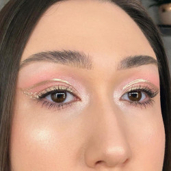 A woman wearing pink eyeshadow with a gold liner